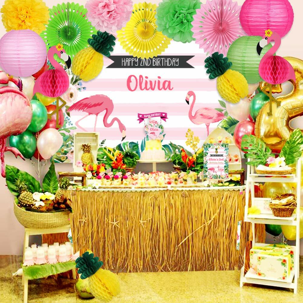 Flamingo pineapple party decorations with paper lanterns, fans, and pom poms in a vibrant birthday setup.