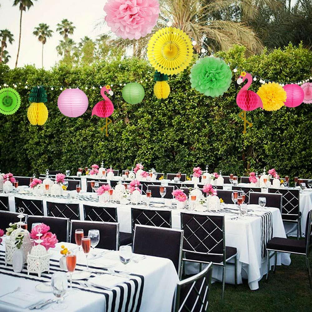 Flamingo pineapple party decorations with colorful paper lanterns, fans, and pom poms displayed at an outdoor table setting.
