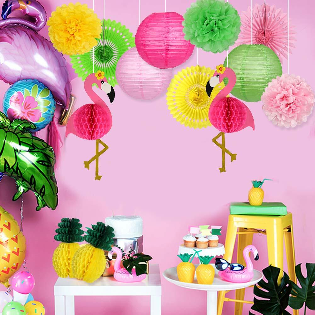 Flamingo pineapple party decorations featuring paper lanterns, fans, and pom poms in vibrant colors against a pink backdrop.