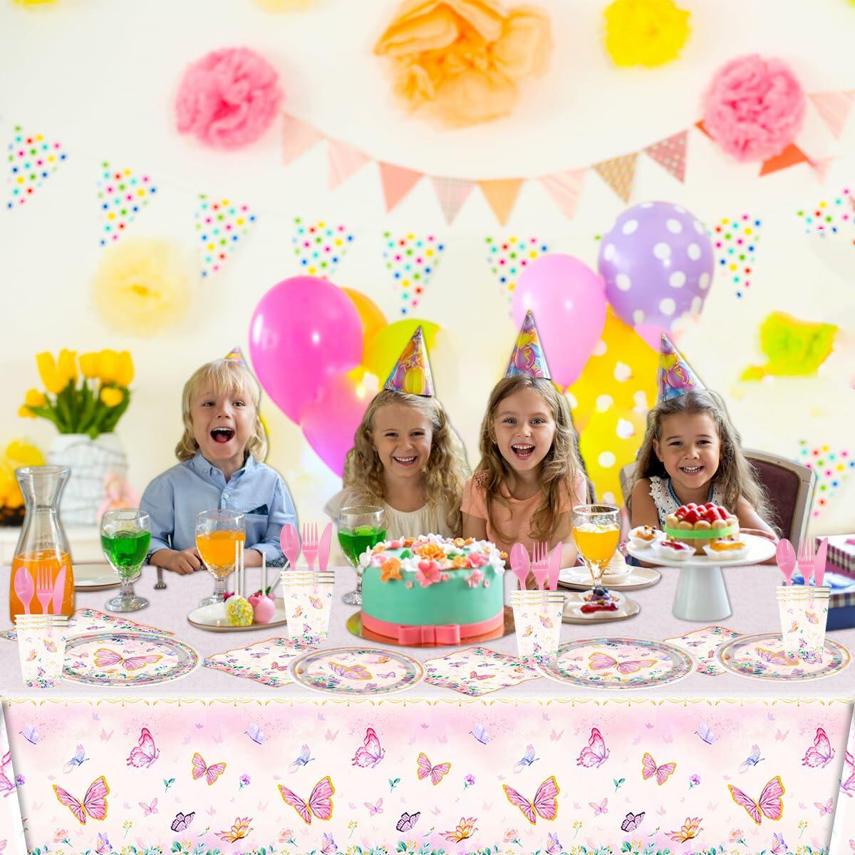 Pink butterfly party tableware set with plates, napkins, and tablecloth displayed at a festive table with children celebra...