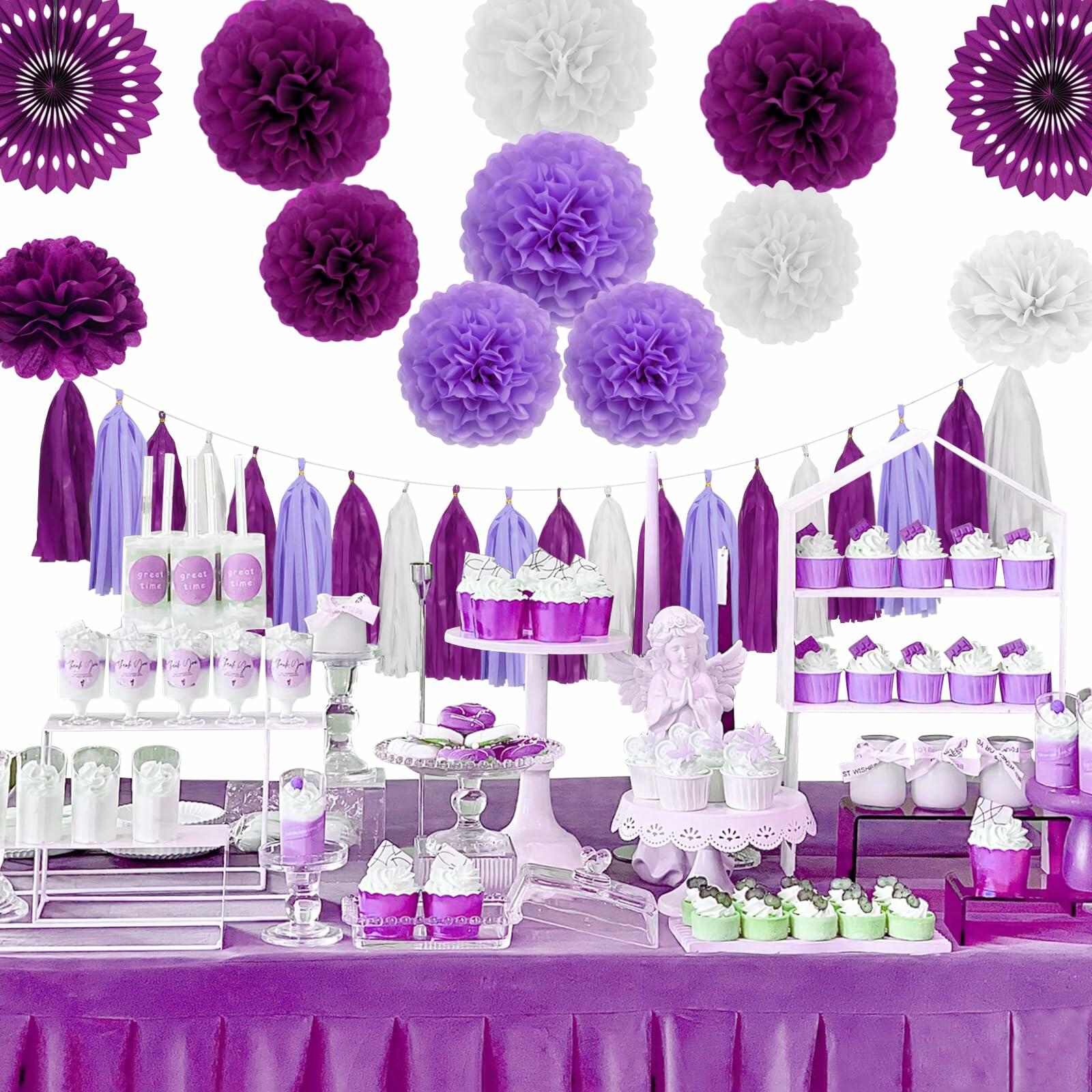 Purple and white tissue paper pom poms arranged above a decorated party table with desserts and purple accents.