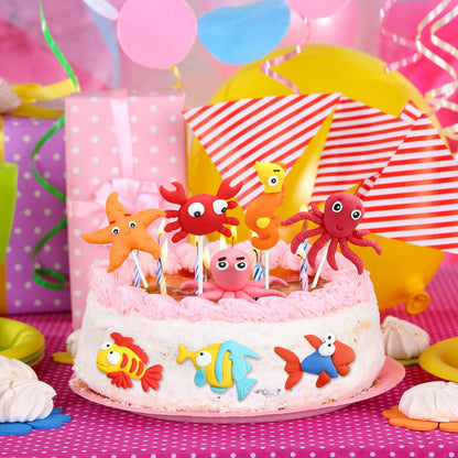 Colorful dinosaur cake toppers in various designs on a pink frosted cake, surrounded by festive party decorations.