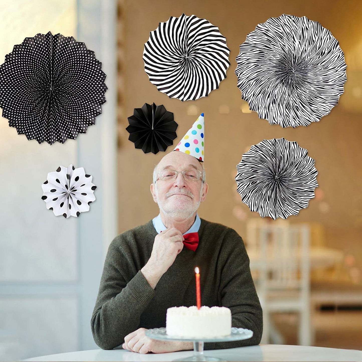 Black hanging paper fans in various patterns, including polka dots and stripes, displayed with a man celebrating a birthday.