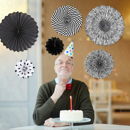 Black hanging paper fans in various patterns, including polka dots and stripes, displayed with a man celebrating a birthday.