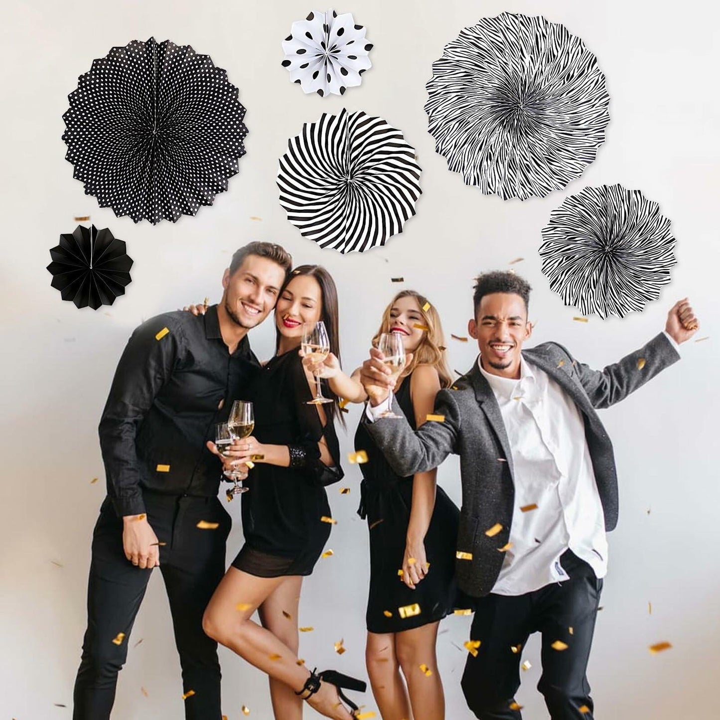 Black hanging paper fans in various patterns, displayed on a wall with four people celebrating at a party.