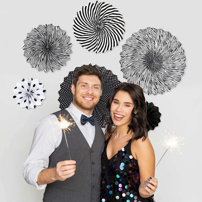 Black hanging paper fans in various patterns and sizes, displayed on a wall with a couple holding sparklers.