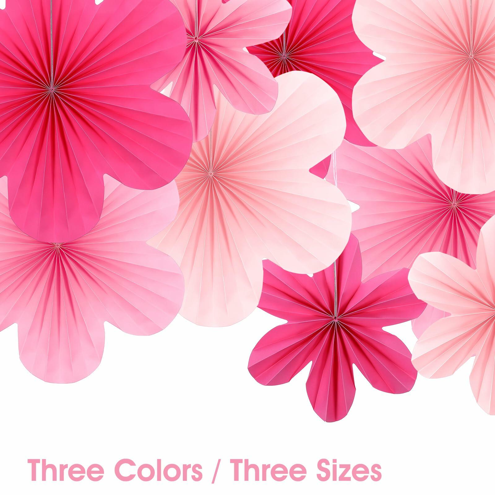 Pink paper fans and flowers in various sizes, featuring shades of pink and white, arranged for party decoration.