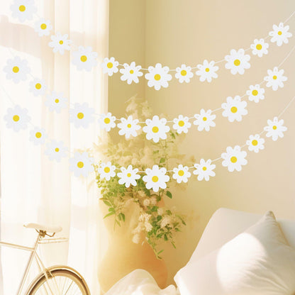Daisy banner garland with white flowers and yellow centers, draped in a sunlit room with a bicycle and vase.