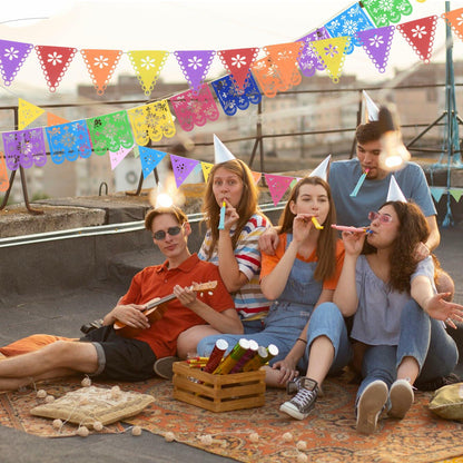 Group of friends celebrating with colorful party hats and decorations at a rooftop.