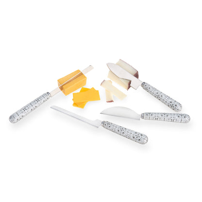 Tile-patterned cheese knife set arranged beside sliced yellow and white cheeses.