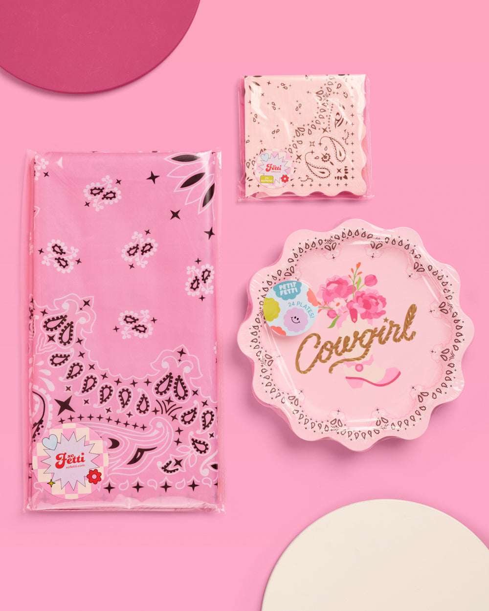 Pink party supplies including napkins, a plate, and a bag on a pink background