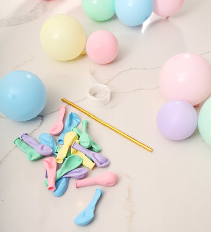 Pastel-colored balloons and a straw on a light surface