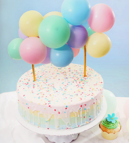 Cake with colorful balloons and sprinkles on a light blue background
