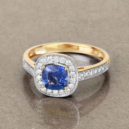 Genuine blue sapphire and white diamond ring in 18K yellow gold, featuring a cushion-cut sapphire and halo setting.