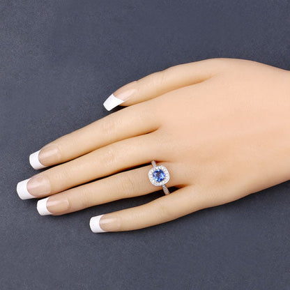 Genuine blue sapphire and white diamond ring in 18K yellow gold, displayed on a hand with manicured nails.