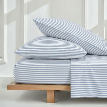 Striped blue and white bedding set on a wooden bed frame with a neutral background.