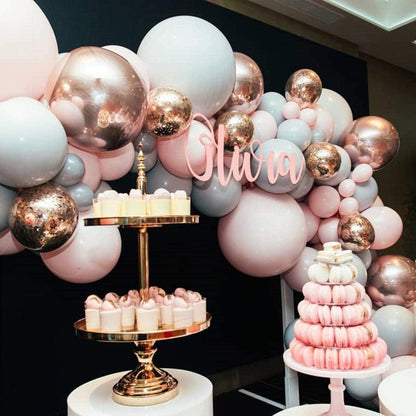 Decorative balloon arch with 'Olivia' and a cake stand with a pink cake and cookies.