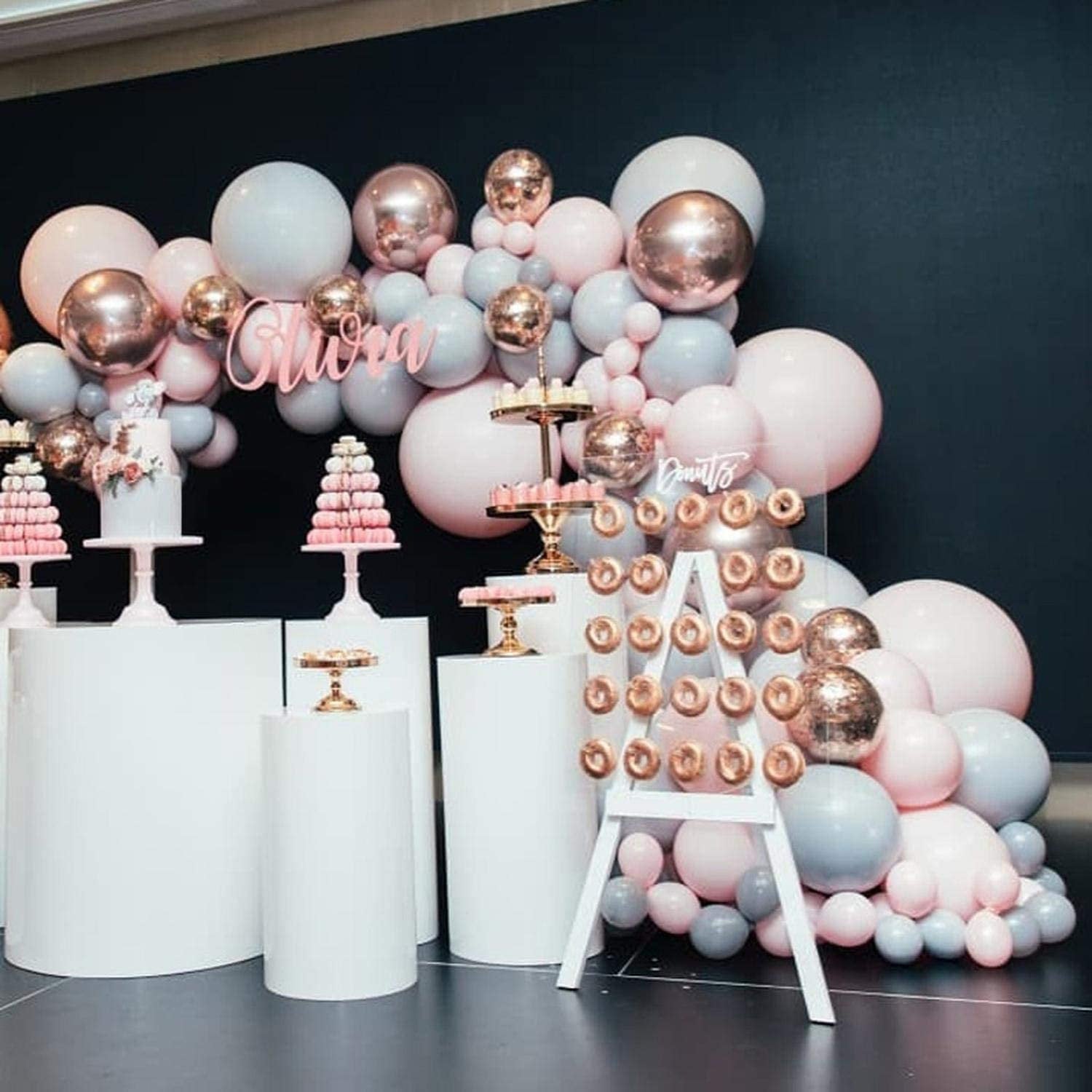 Decorative setup with balloons, cake stands, and a name sign on a dark background