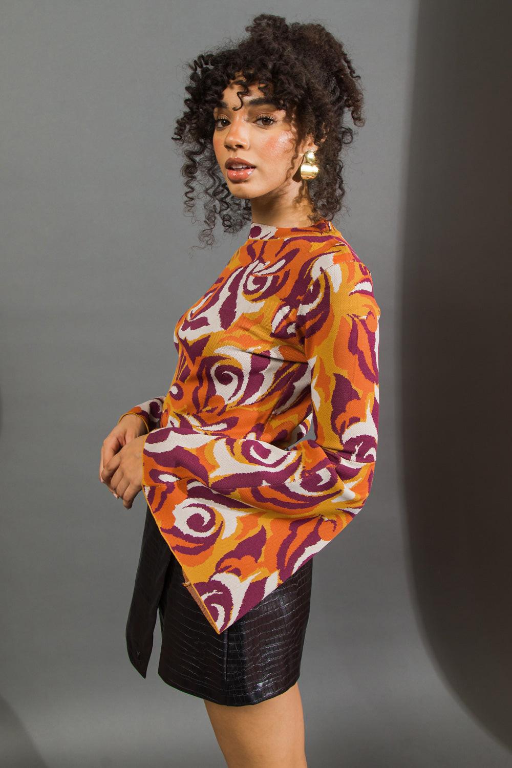 Woman wearing a colorful patterned top against a gray background