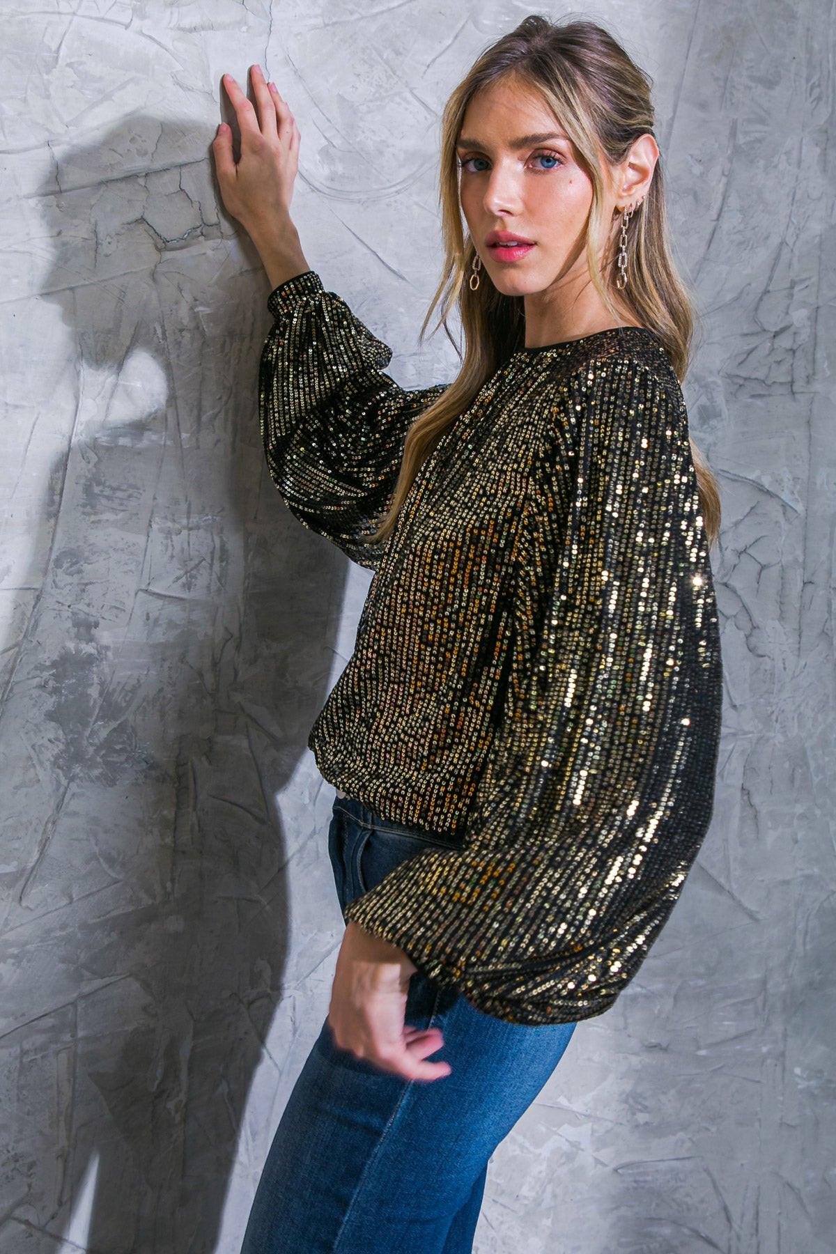 Woman wearing a gold sequin top against a textured gray wall