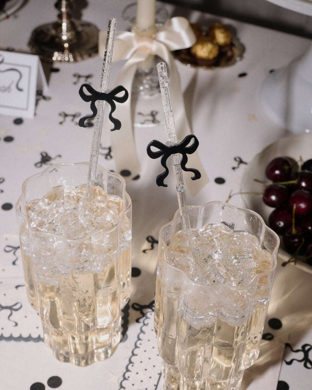 Two glasses with decorative straws on a table with black and white decorations.