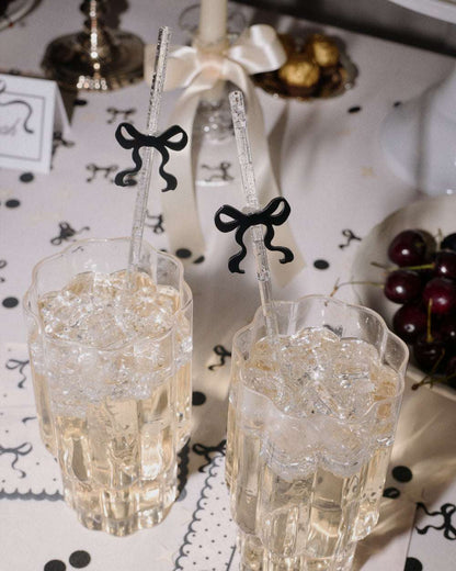 Two glasses with decorative straws on a table with black and white decorations.