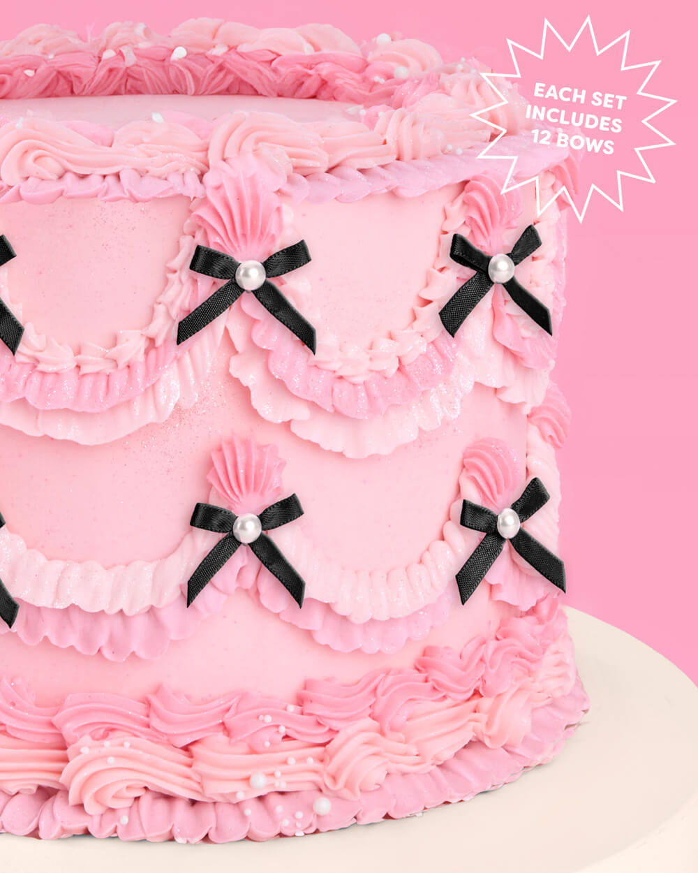 Pink cake with black bows and pearls on a pink background
