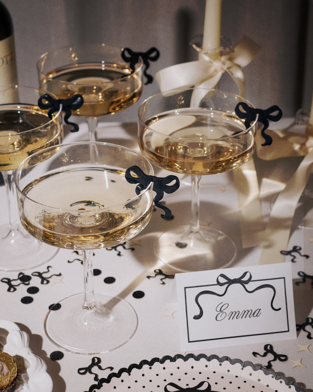 Cocktail glasses with a white liquid on a tablecloth with black bow decorations.
