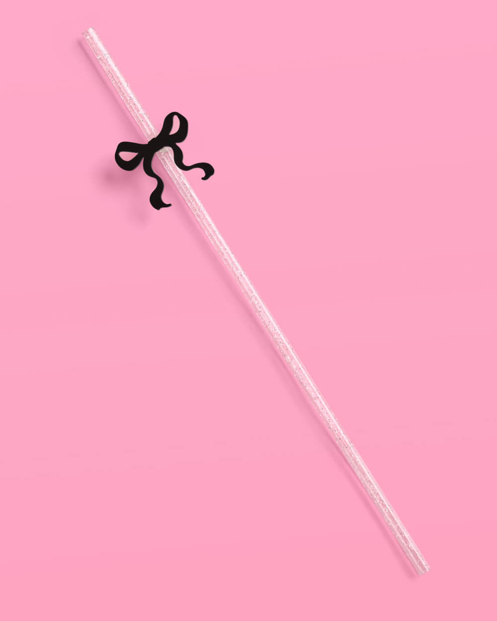 Clear straw with a black bow on a pink background