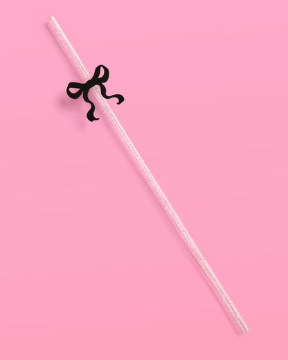 Clear straw with a black bow on a pink background
