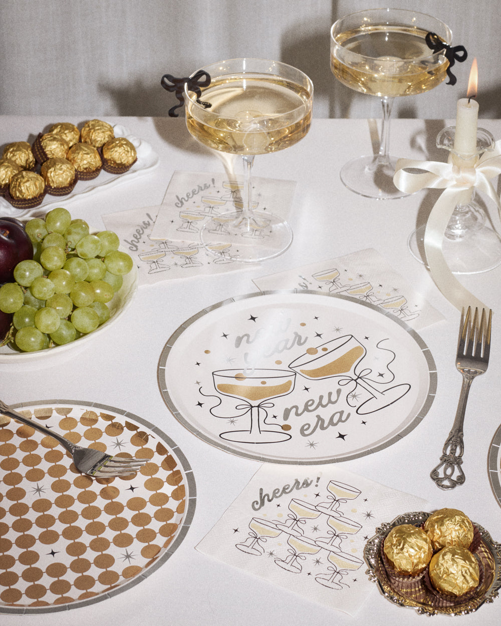 Decorative table setting with glasses of champagne, snacks, and a 'New Era' placemat.