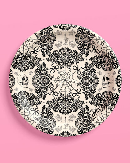 Decorative plate with black and white skull and lace pattern on a pink background