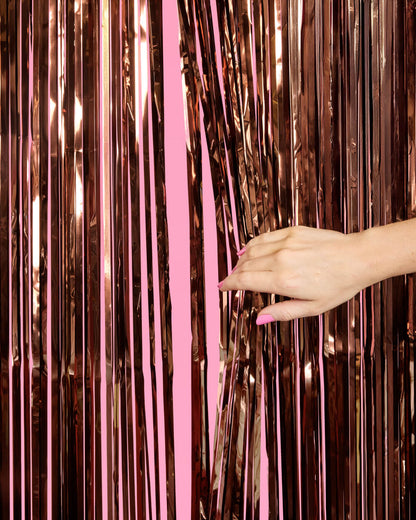 Hand reaching towards a rose gold tinsel curtain