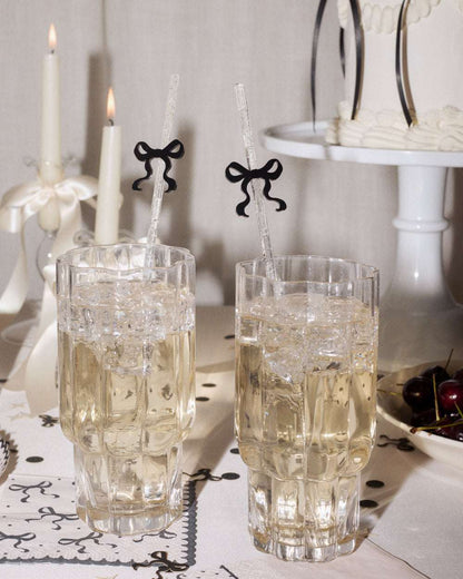 Two crystal glasses with white liquid on a decorative table setting with candles and a cake stand.