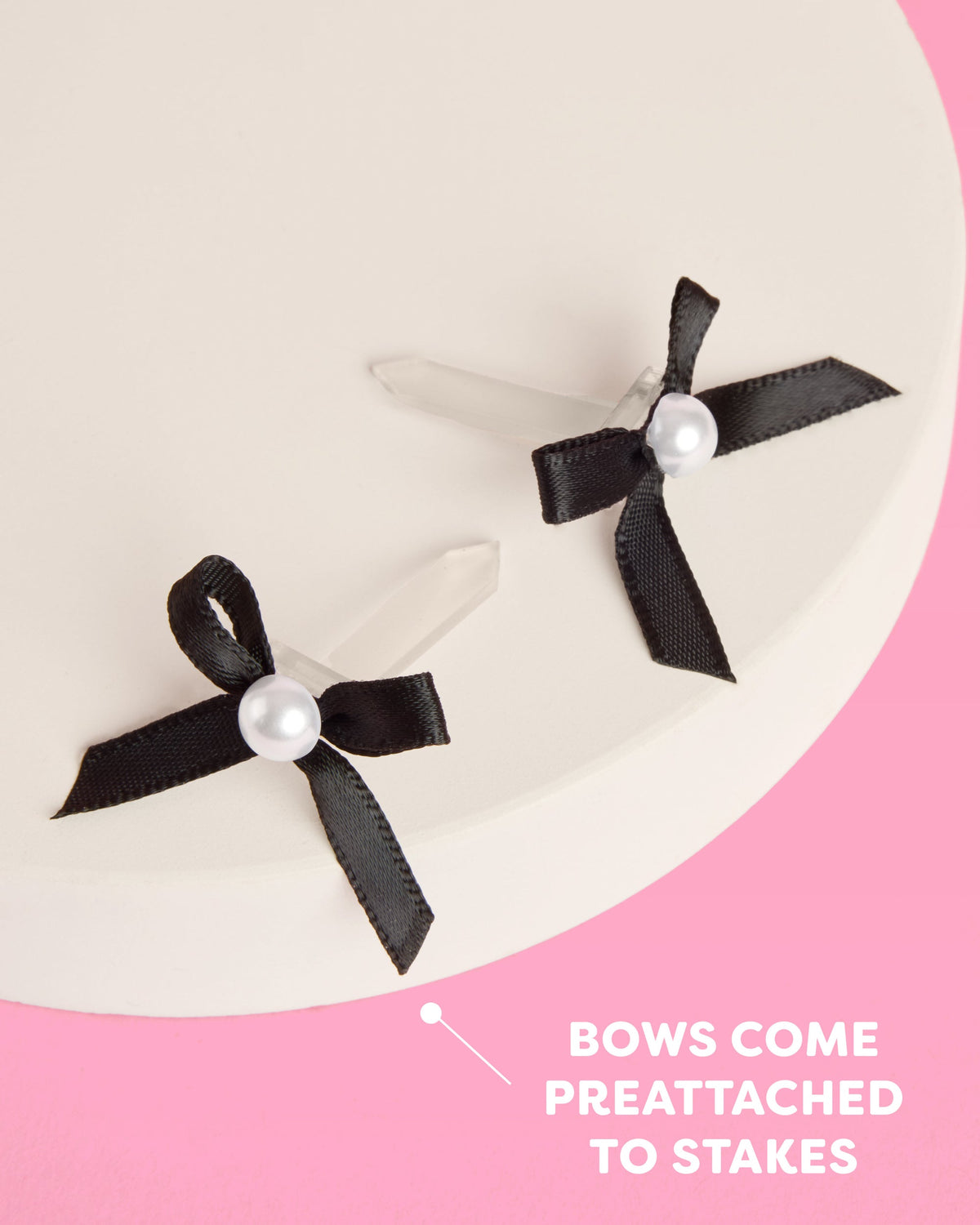 Two black bows with pearls on a pink and white background