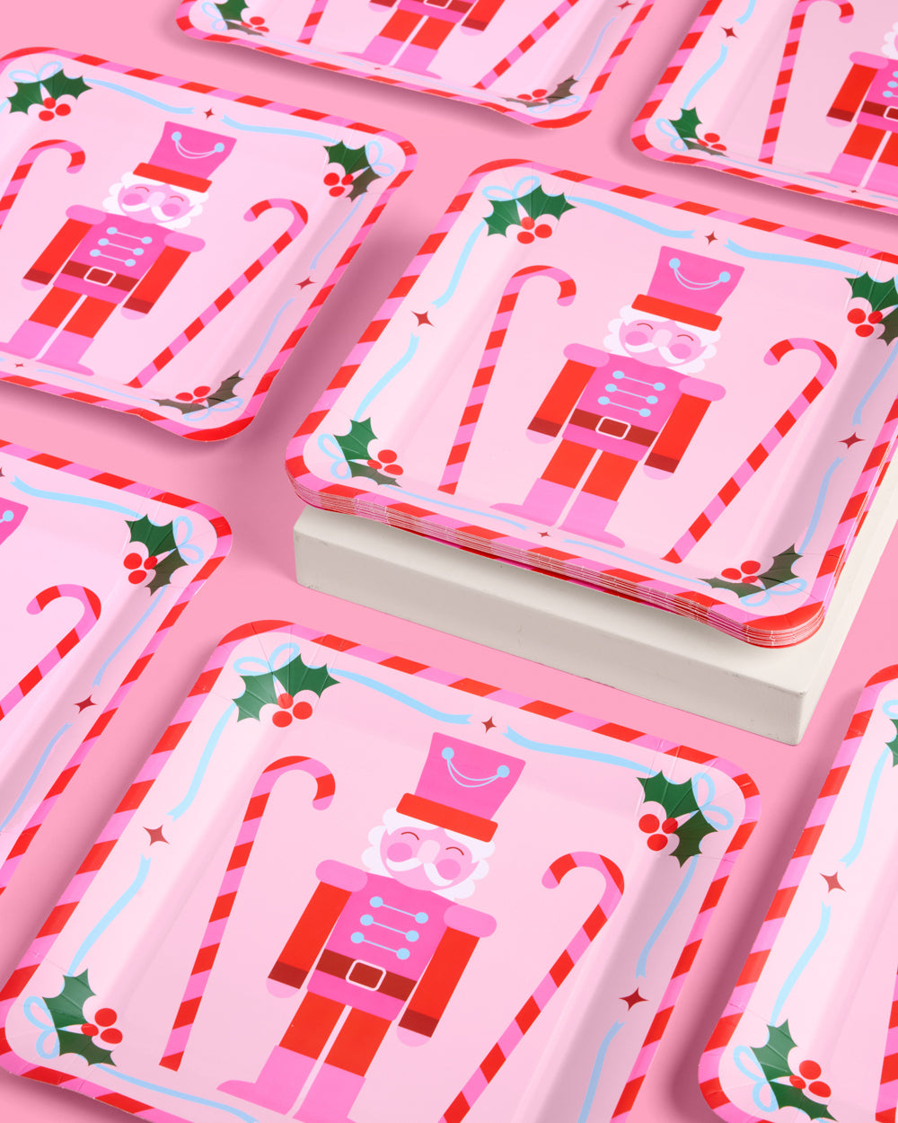 Set of Christmas-themed paper plates with nutcracker design on a pink background
