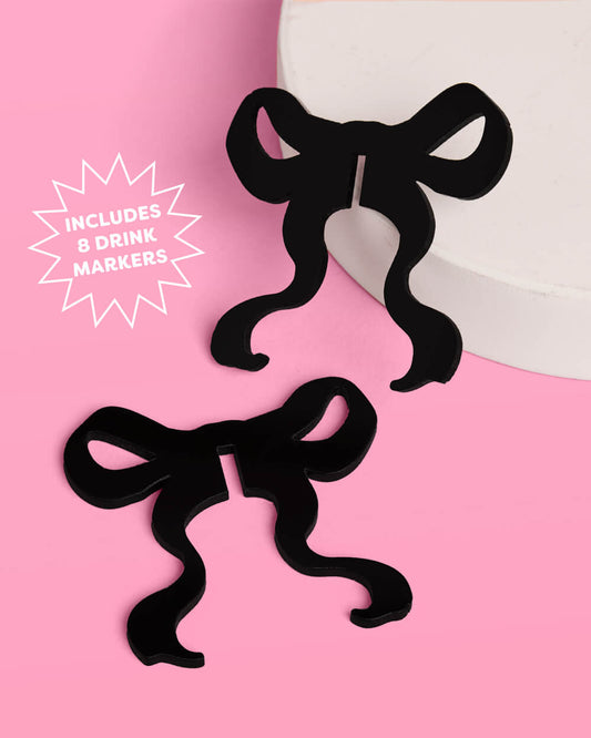 Black bow-shaped drink markers on a pink background with text indicating quantity.