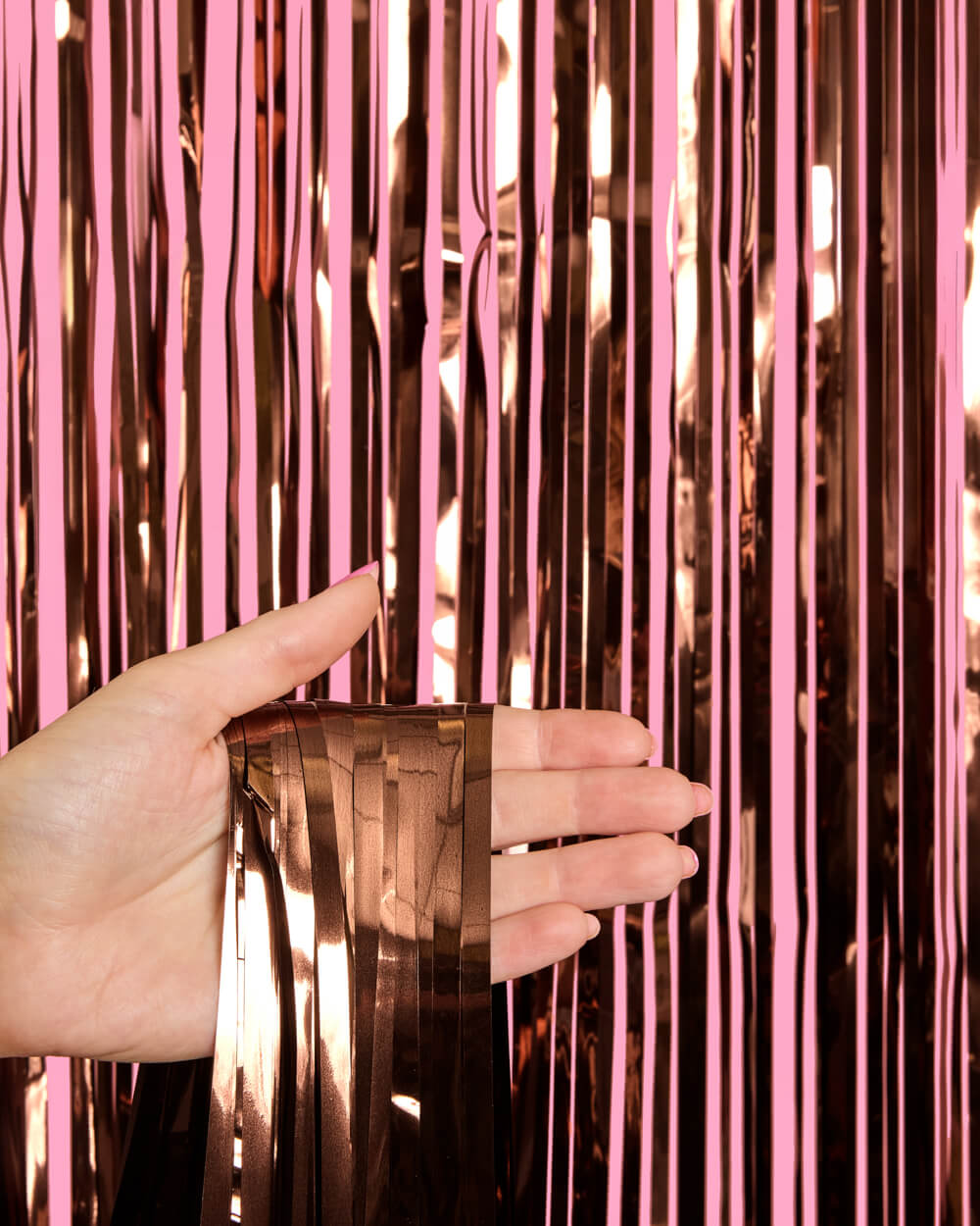 Hand touching pink and rose gold tinsel curtain