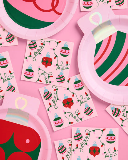 Christmas-themed party supplies including plates and stickers on a pink background