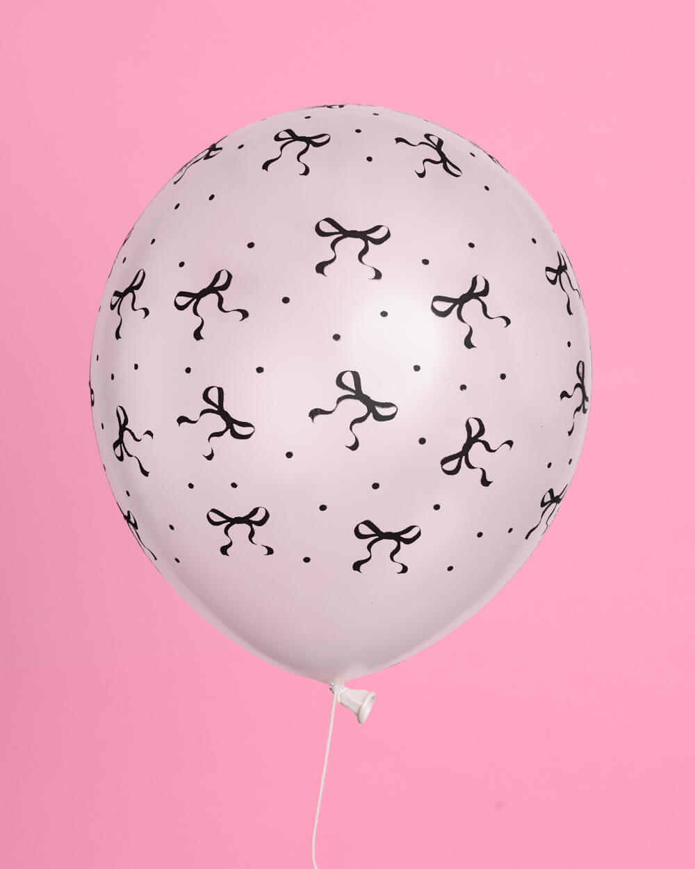 White balloon with black bow pattern on a pink background