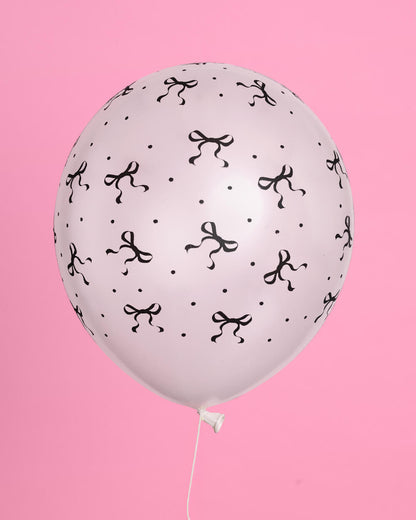 White balloon with black bow pattern on a pink background