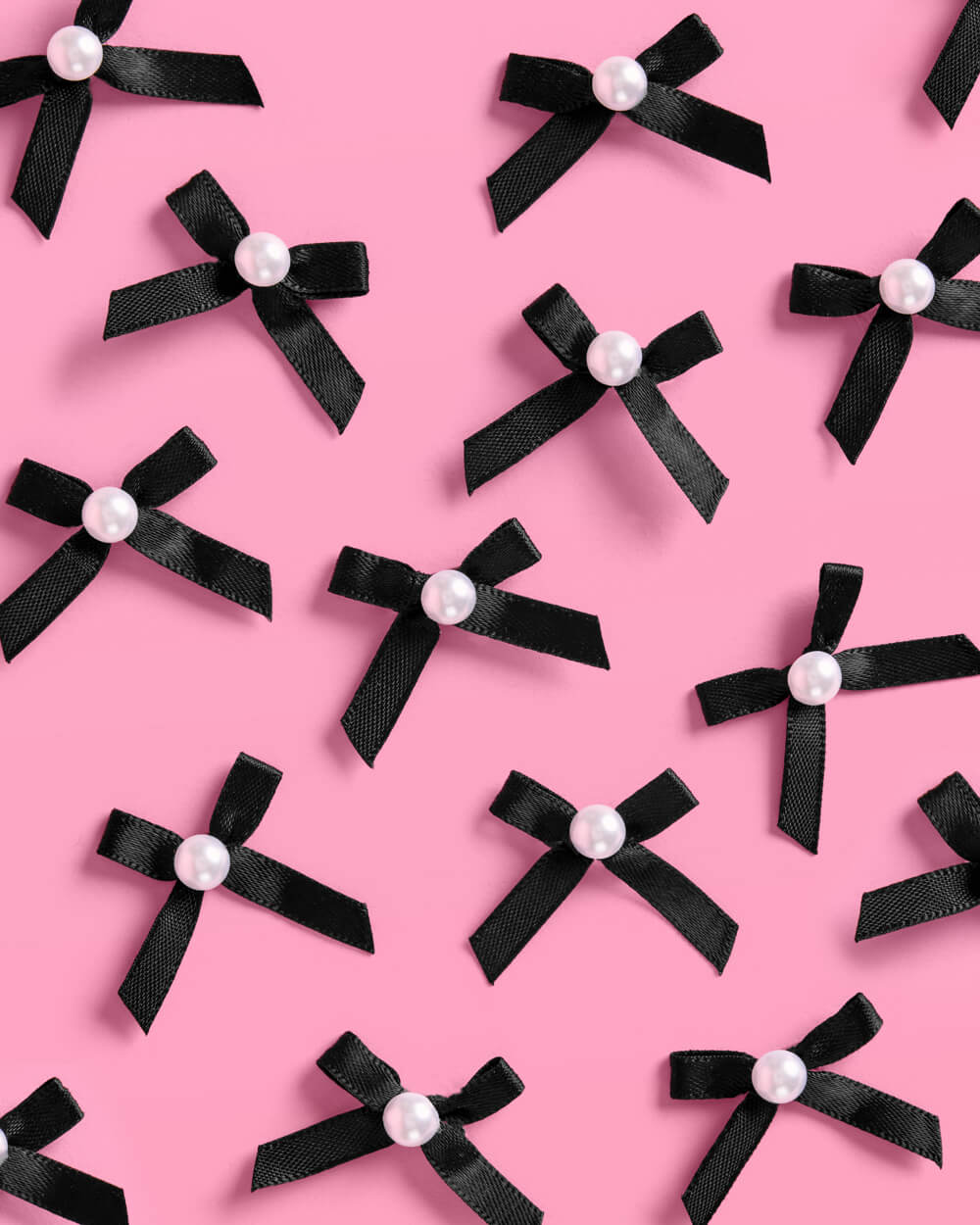 Black bows with white pearls on a pink background