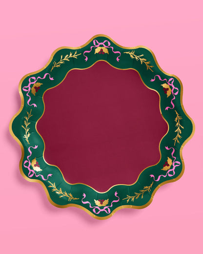 Decorative round mirror with a green frame featuring floral and ribbon designs on a pink background
