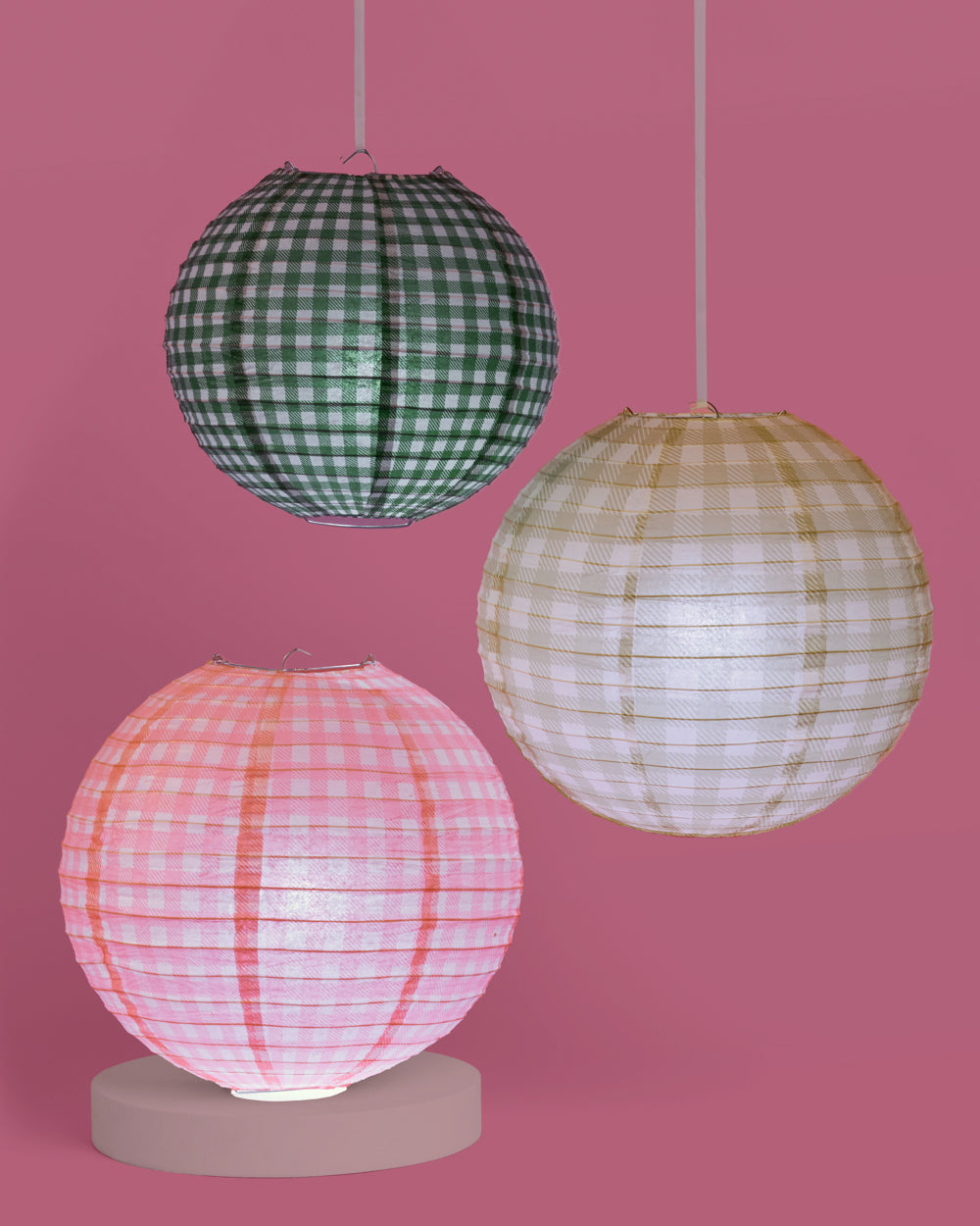 Three spherical paper lamps with checkered patterns on a pink background
