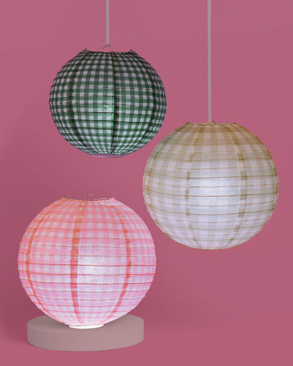Three spherical paper lamps with checkered patterns on a pink background
