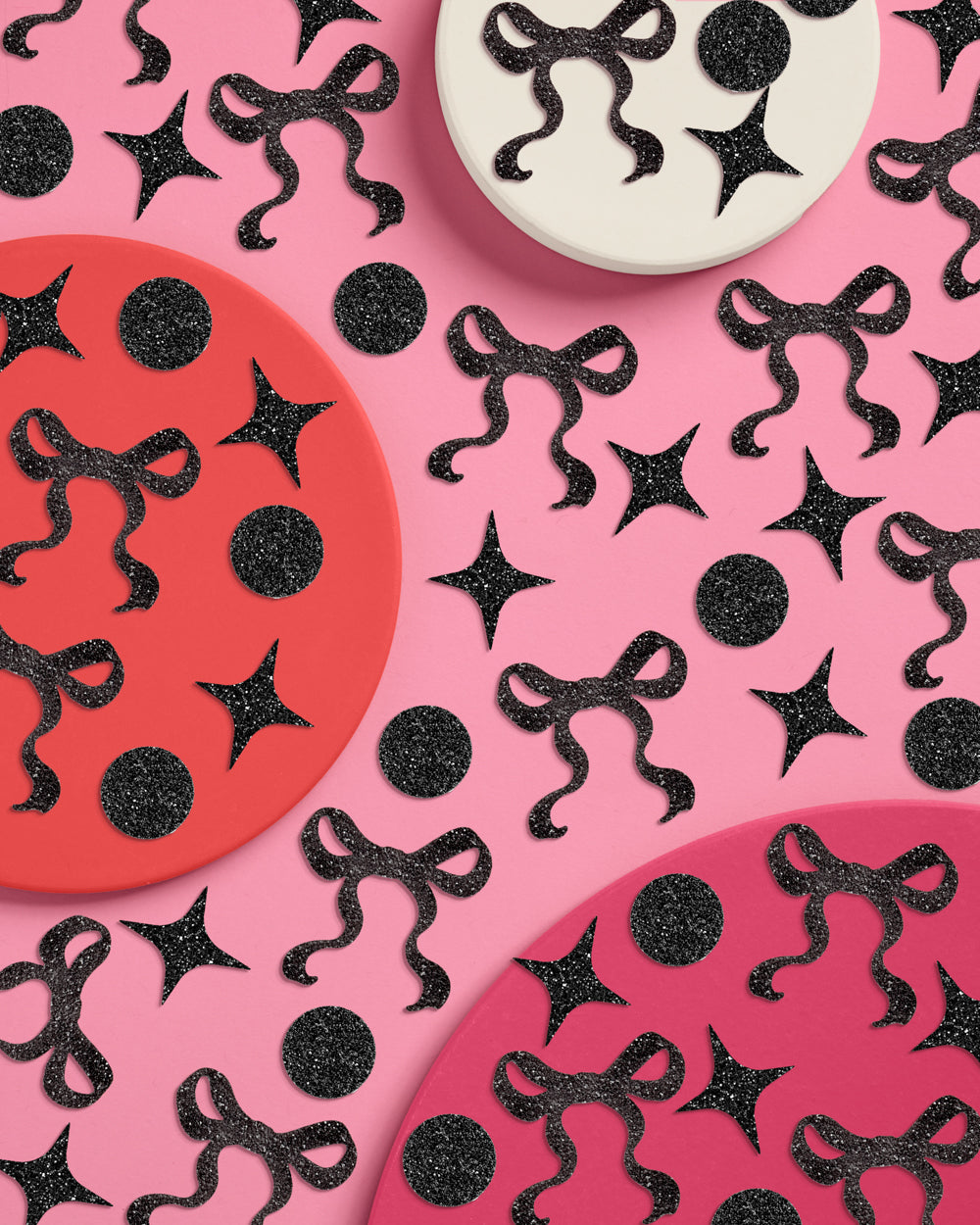 Decorative paper plates with black ribbons and stars on a pink background