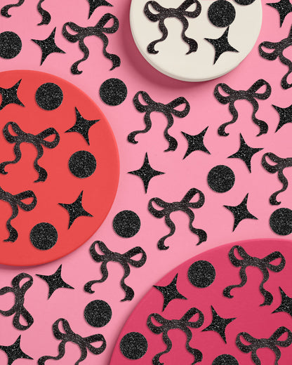 Decorative paper plates with black ribbons and stars on a pink background