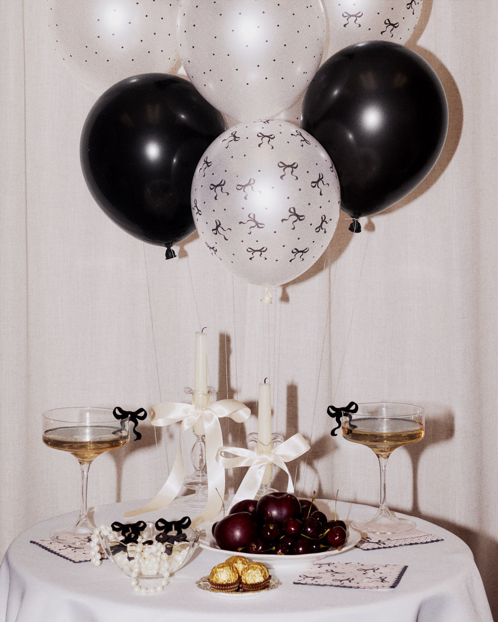 Decorative table setting with black and white balloons, candles, and wine glasses.