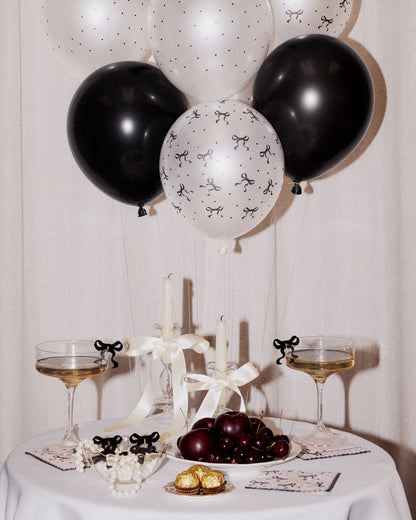Decorative table setting with black and white balloons, candles, and wine glasses.