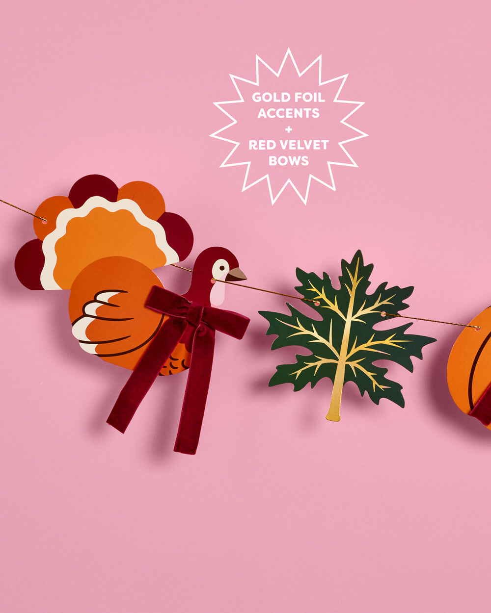 Autumn-themed paper garland with a turkey, maple leaf, and pumpkin cutouts on a pink background, with text reading 'GOLD FOIL ACCENTS + RED VELVET BOWS'.